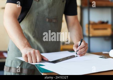Cropped shot of male artisan wearing apron while creating patterns in tanners workshop, copy space Stock Photo