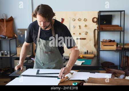 Portrait of male artisan wearing apron while creating patterns in tanners workshop, copy space Stock Photo