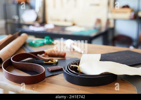 Background image of handmade leather belts and tools on wooden desk in tanners workshop, copy space Stock Photo
