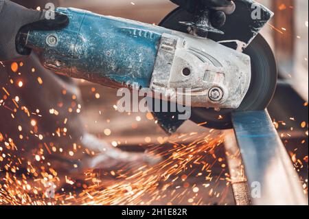 Construction worker using Angle Grinder cutting Metal at construction site . Stock Photo