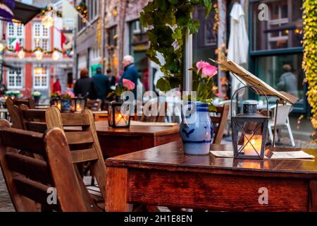 MAASTRICHT, THE NETHERLANDS - NOVEMBER 22, 2016: Empty dinner tables in front of a restaurant with tourists in the background in Maastricht Stock Photo
