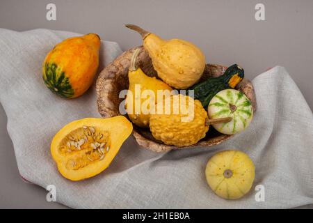 Ceramic bowl with selection of small decorative pumpkins. Orange pumpkins on linen tablecloth. Stock Photo
