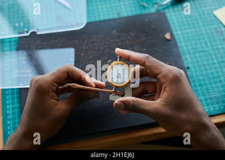 Top view of unrecognizable African-American man creating handmade leather bag while working in leatherworkers workshop, copy space Stock Photo