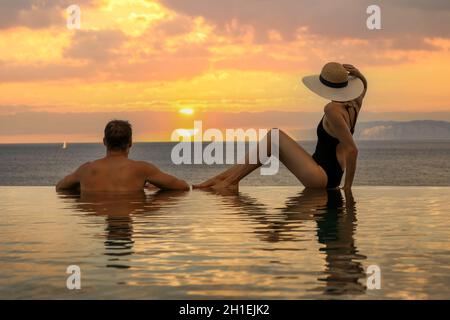 honeymoon vacation - couple enjoying romantic sunset in infinity pool at luxury resort Stock Photo