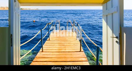 The wooden bridge and staircase in the water at the beach with coral reef at sunny day at Sharm el Sheikh, Egypt Stock Photo