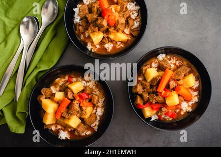 Bowls of Mechado Filipino Beef Stew Served Over White Rice: Braised beef in tomato sauce with chunks of potatoes and carrots Stock Photo