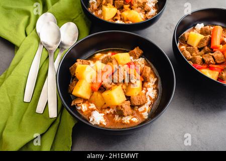 Bowls of Mechado Filipino Beef Stew Served Over White Rice: Braised beef in tomato sauce with chunks of potatoes and carrots Stock Photo