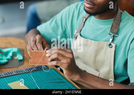 Cropped portrait of young African-American artisan working with leather in leatherworkers workshop, copy space Stock Photo