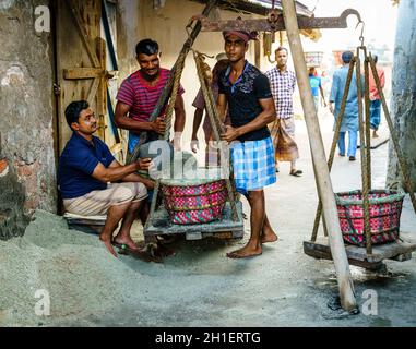 Chittagong, Bangladesh, December 22, 2017: Men weighing baskets with salt at a factory in Chittagong, Bangladesh Stock Photo