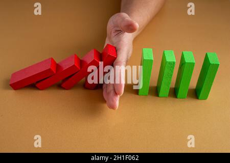 Close up business woman hand stopping wooden blocks from falling. Concept of risk and crisis management in business life. Stock Photo