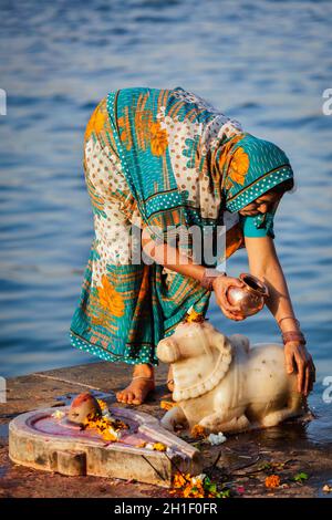 MAHESHWAR, INDIA - APRIL 26: Indian woman performs morning pooja on sacred river Narmada ghats on April 26, 2011 in Maheshwar, Madhya Pradesh, India. Stock Photo