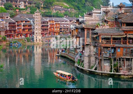 Chinese tourist attraction destination - Feng Huang Ancient Town (Phoenix Ancient Town) on Tuo Jiang River with Wanming Pagoda tower and tourist boat. Stock Photo