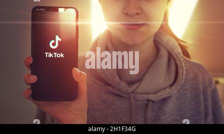 KYIV, UKRAINE-JANUARY, 2020: Tiktok on Smart Phone Screen. Young Girl Showing Mobile Phone Screen with Tiktok on it while Looking at the Camera. Focus Stock Photo