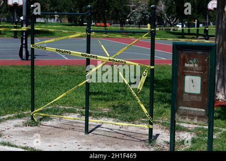 Pompano Beach, FL, USA - April 7, 2020: Yellow and black caution tape blocking access to chin-up bars during the Covid-19 pandemic. Caution sign tape Stock Photo