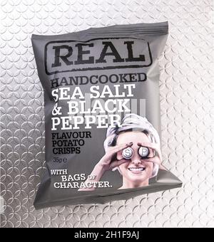 SWINDON, UK - SEPTEMBER 28, 2018: A Packet of REAL Handcooked Sea Salt and Pepper Flavour Potato Crisps on a silver backgound. Stock Photo