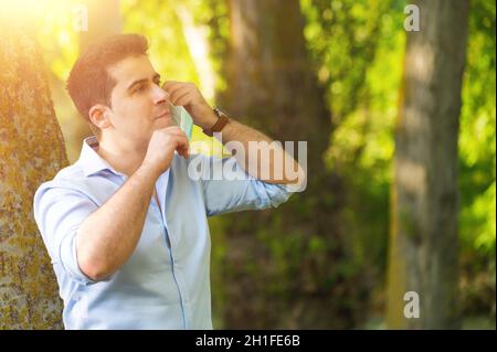 Young man standing in the park removing protective face mask celebrating victory over coronavirus outside in open air. End of quarantine. Remove mask. Stock Photo
