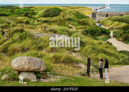 Tourists on the sandy path to the Grenen Peninsula observe the tomb of the Danish poet and playwright Holgher Drachmann. Skagen, Denmak Stock Photo