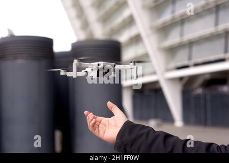 hand with drone on city background outdoors. exploring new building with innovative technology taking aerial photos and videos from above Stock Photo