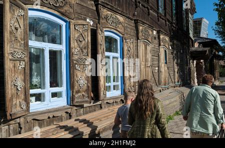 Small group of people walking along one of the traditional wooden houses in Ulan-Ude. Republic of Buryatia, Russia Stock Photo