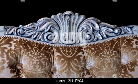 Ornament woodcarving in classic furniture with soft plush fabric upholstery. Isolated on black background. Stock Photo