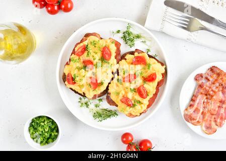Scrambled eggs with microgreen and tomatoes on bread over light stone background. Top view, flat lay Stock Photo