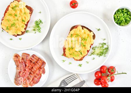 Scrambled eggs with microgreen on bread and fried bacon. Top view, flat lay Stock Photo