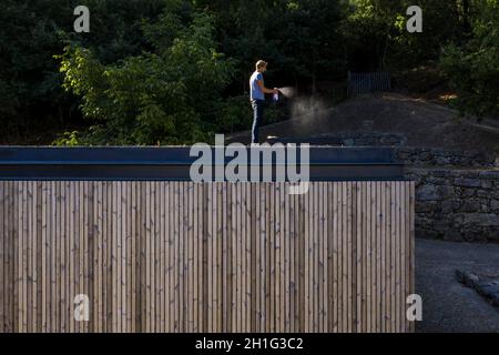 Timber clad facade and person standing on roof. Pavilion House, Guimarães, Portugal. Architect: Diogo Aguiar Studio, 2019. Stock Photo