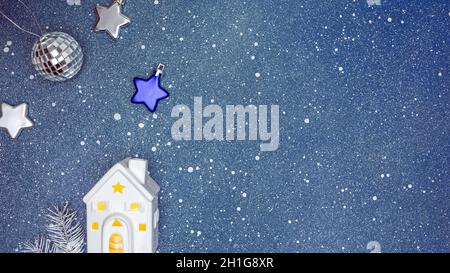 festive christmas decorations on blue background. illuminated toy house, silver ball and stars. Stock Photo