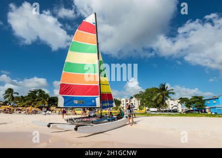 Bridgetown, Barbados - December 18, 2016: Brownes beach at ocean coast with people and colorful sail on a yacht at sunny day in Carlisle bay, Bridgeto Stock Photo