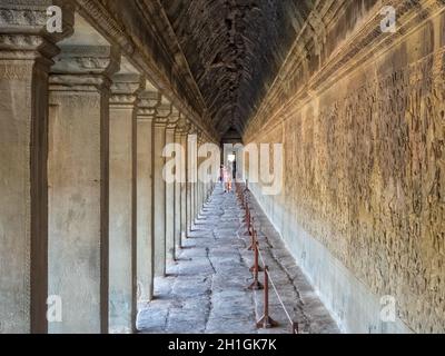 Tourists admire the bas-reliefs in the West gallery of Angkor Wat - Siem Reap, Cambodia Stock Photo