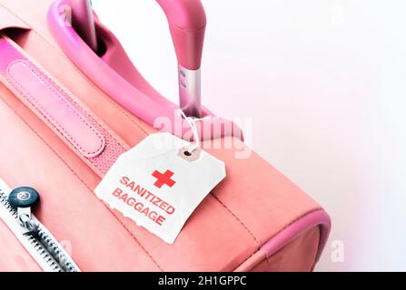 a red suitcase with a paper tag indicating that the baggage has been sanitized. Virus prevention while traveling Stock Photo