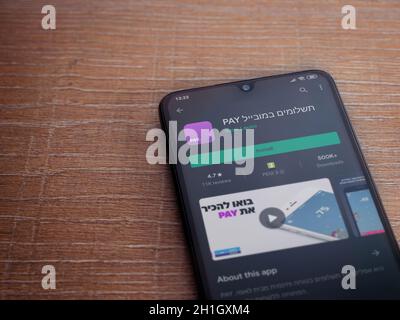 Lod, Israel - July 8, 2020: PAY app play store page on the display of a black mobile smartphone on wooden background. Top view flat lay with copy spac Stock Photo