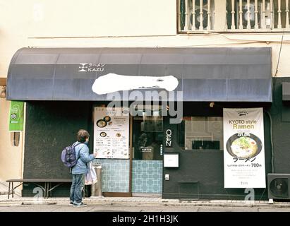 Kyoto, Japan - 09 February, 2020: Front entrance view of traditional ramen restaurant in Japanese city of Kyoto with customer looking at outdoor menu Stock Photo