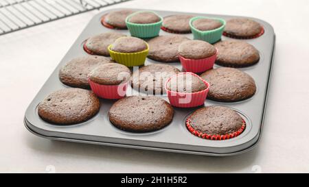 Fresh baked chocolate cupcakes close up on baking pan on light grey background Stock Photo