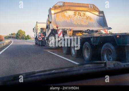 Oversize load truck transporting a huge excavator machine. View from the inside of the car Stock Photo