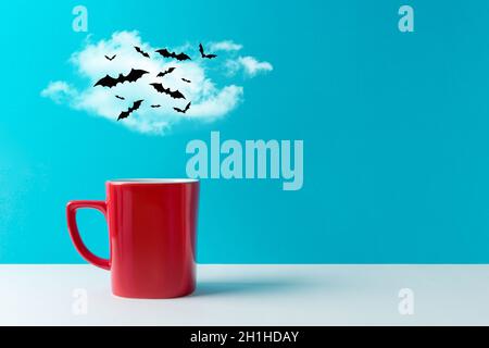 Halloween celebration concept with cup of coffee or hot drinks and bats on white table. Minimal holiday concept. Stock Photo