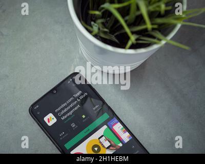 Lod, Israel - July 8, 2020: Modern minimalist office workspace with black mobile smartphone with Monday app play store page on marble background. Top Stock Photo