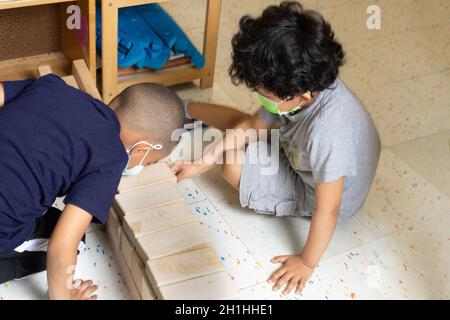 Education Preschool 4-5 year olds two boys playing with wooden blocks building Stock Photo