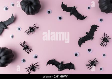 Creative pink background made of bats, spiders, and pumpkins. Minimal Halloween concept. Flat lay. Stock Photo