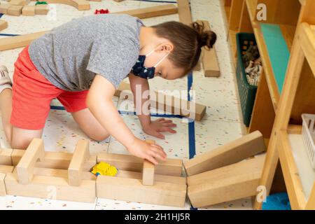 Education Preschool 4-5 year olds boy playing by himself, building with wooden blocks Stock Photo