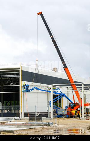 a sandwich panel wall mounting with the help of a modern telescopic crane and mobile self propelled hydraulic lifting platform Stock Photo