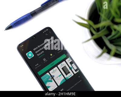 Lod, Israel - July 8, 2020: Modern minimalist office workspace with black mobile smartphone with Mint Browser app play store page on white background. Stock Photo