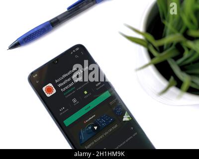 Lod, Israel - July 8, 2020: Modern minimalist office workspace with black mobile smartphone with AccuWeather app play store page on white background. Stock Photo