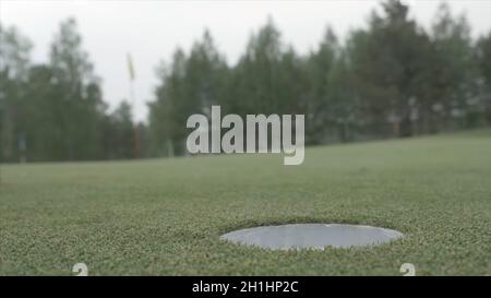 Ball rolling into the hole. Golf ball about to fall into a hole. Golf ball rolling into the hole on a gold course on a bright sunny day f Stock Photo