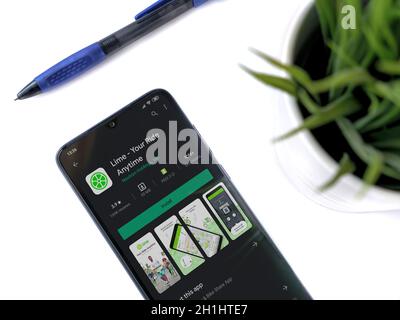 Lod, Israel - July 8, 2020: Modern minimalist office workspace with black mobile smartphone with Lime app play store page on white background. Top vie Stock Photo