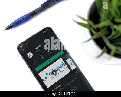 Lod, Israel - July 8, 2020: Modern minimalist office workspace with black mobile smartphone with Cellopark app play store page on white background. To Stock Photo