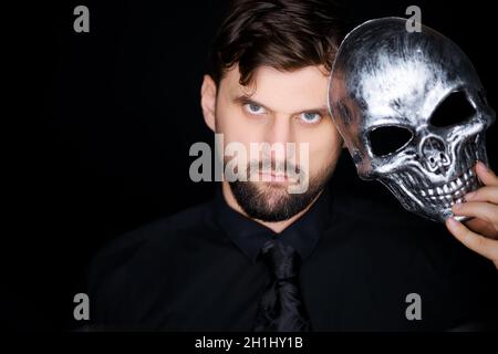 a man standing on a black background wears a skeleton mask Stock Photo