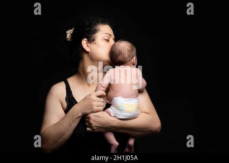 Young mother embraced a newborn baby boy and kissing him, parenting concept Stock Photo