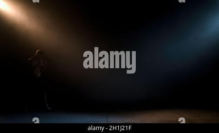 Boxer doing shadow Boxing in a dark room. Man of athletic build makes a punch. Dramatic lighting. Stock Photo