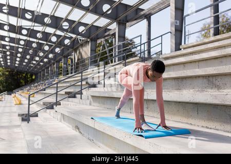 African American woman doing yoga near the stadium in the morning, active lifestyle performs fitness exercises Stock Photo